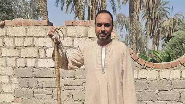 صورة لأحد الأهالي ممسكاً بثعبان بعد القضاء عليه     